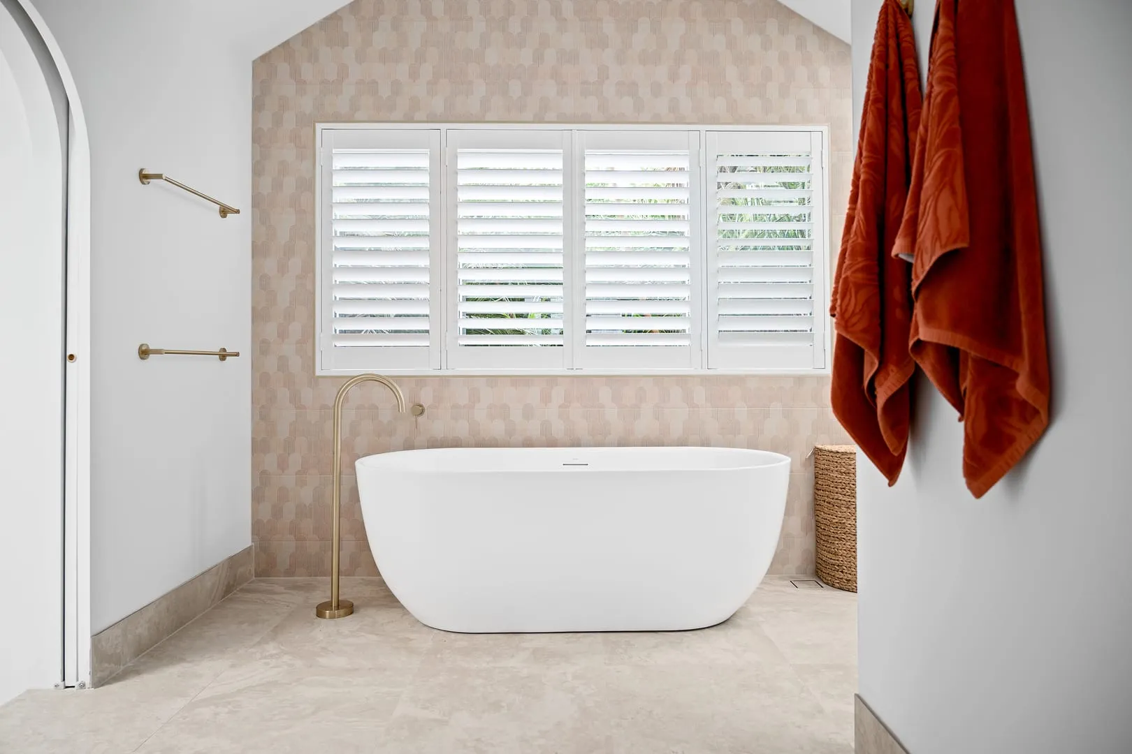Freestanding tub beneath plantation shutters
